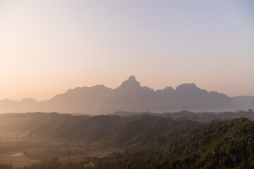 pink hazy sunrise over jagged mountains in Vang Vieng, the adventure capital of Laos