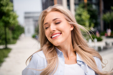 Photo of adorable young blonde hair smiling woman wearing blue shirt satisfaction spring vacation walking outside her residential complex