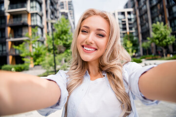 Self portrait of happy young smiling woman traveling with camera making shot she visited residential complex modern design and park
