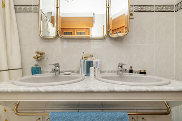 Old bathroom with two sinks integrated into the marble countertop and triptych mirror