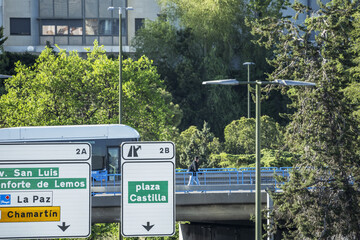 Large directional indicator signs on the road and a pedestrian traveling on an overpass