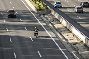 A motorcycle traveling alongside other vehicles on a highway with several lanes in each direction