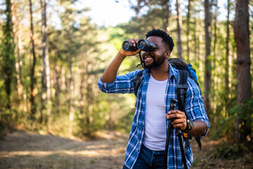 Young man enjoys using  binoculars and hiking  in nature.