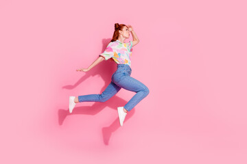 Full body length photo of red hair funky hipster curious looking far away jumping air trampoline isolated on pink color background