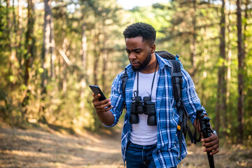 Worried hiker got lost and he is using a phone to find right direction while hiking in the nature.