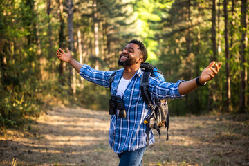 Happy young man hiker with arms raised enjoys in the nature.