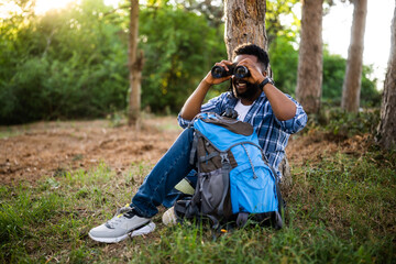 Young hiker using  binoculars while resting  in nature.