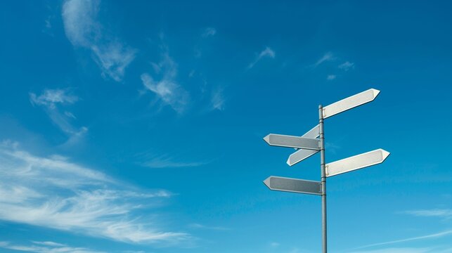 Blank directional signposts against a blue sky with clouds.