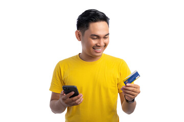 Smiling young Asian man holding bank credit card and mobile phone isolated on white background