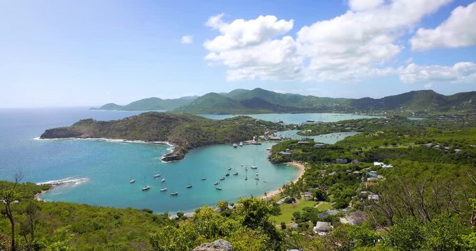 A beautiful tourist woman enjoys the panoramic view over the landscape of Antigua island with English Harbour and Shirley heights