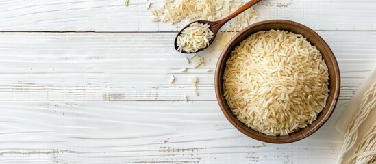 Raw basmati rice and a spoon placed in a bowl on a white wooden table, with room for text.