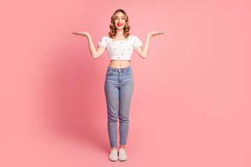 Fototapeta premium Full body photo of pretty young girl compare hold empty space wear trendy white outfit hairdo isolated on pink color background