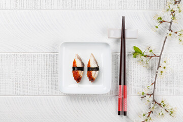 Eel sushi adorned with cherry blossom branch and chopsticks, epitomizing Japanese food culture