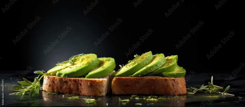 Poster a copy space image depicts toasted bread topped with fresh green avocado on a textured black surface