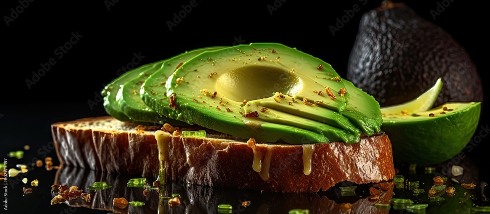 Poster a copy space image depicts toasted bread topped with fresh green avocado on a textured black surface