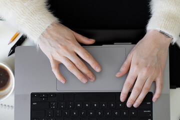 Female hands typing on laptop keyboard. Top view of office desktop