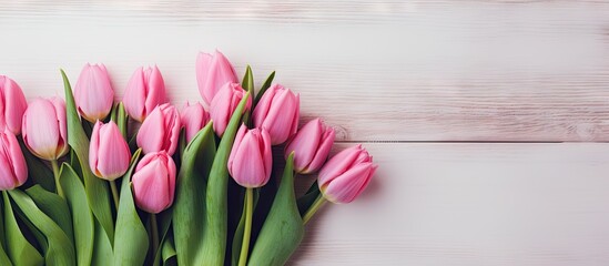 A bunch of pink tulips arranged on a white wooden surface allowing room for a text message. with copy space image. Place for adding text or design