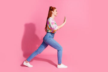 Full length photo of cheerful strong woman wear print shirt push invisible object in empty space isolated on pink color background