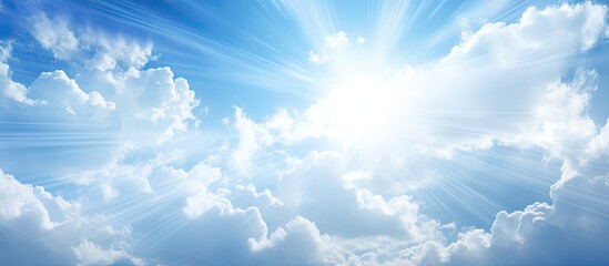 A copy space image of sunlight filtering through white clouds against a blue sky backdrop