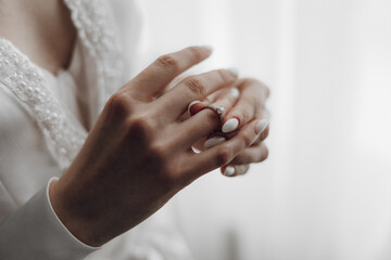 A woman is holding a ring in her hand. The ring is white and has diamonds on it. The woman is...