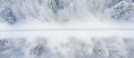 A drone captures a winter landscape as it shoots a top view of a snow covered rural country road in the north The image offers ample copy space