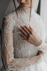 A woman is wearing a white dress with a lace collar and a long sleeve. She is holding her arm out...