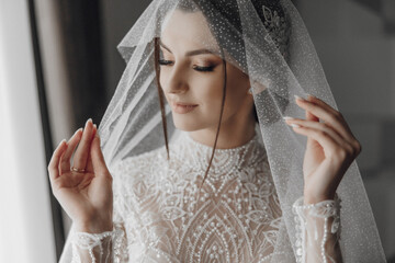 A woman in a wedding dress is wearing a veil and holding her hands up. Concept of elegance and...