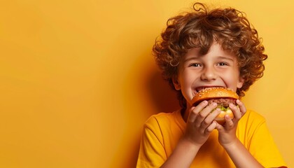 Young boy savoring delicious hamburger on gentle colored backdrop with ample room for text placement