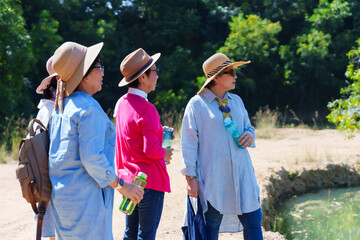 Four senior companions, sporting sun hats and carrying water bottles, pause for a moment's rest,...