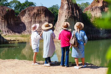 Senior friends in sunhats observe geological marvels, reflection in calm waters adds to serene...