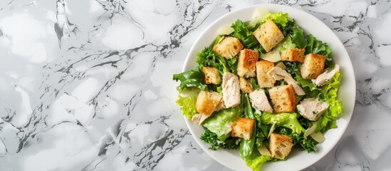 Caesar Salad placed on a marble table from a top view, with empty space for text. Freshly made chicken Caesar salad served with toasted croutons.