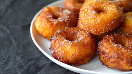 Delicious kuih keria, a malaysian sweet potato doughnut, close-up on a white plate against a dark background