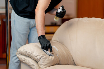 professional cleaning of an apartment cleaner polishes a leather sofa with polish