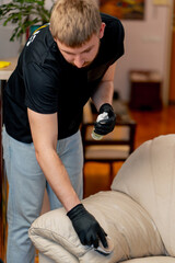 professional cleaning of an apartment cleaner polishes a leather sofa with polish