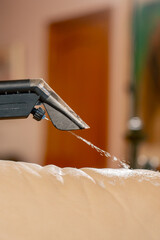 professional cleaning close up in an apartment cleaner wets a textile sofa before washing