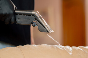 professional cleaning close up in an apartment cleaner wets a textile sofa before washing