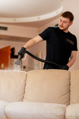 professional cleaning in an apartment cleaner wets a textile sofa before washing