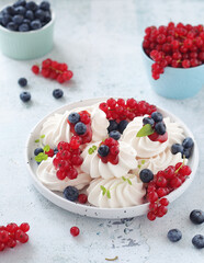 White sweet traditional merenques with berries on the plate	