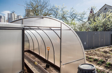 A new greenhouse made of polyethylene and polycarbonate with new beds made of Wood-polymer composite. Preparing for the spring garden season. Installation of a greenhouse in a suburban area.