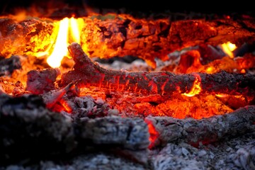 The hot red coals from the campfire are smoldering