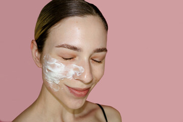 Beauty, skin care concept.  Face cream on a girl's face pink background