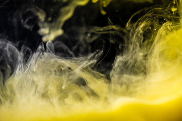 clouds of yellow smoke on a black background, clouds of paint in water, aquarium, abstract background, texture