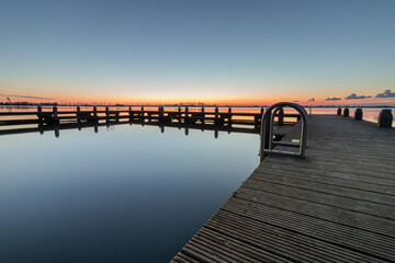 Square swimming pontoon in the Alkmaardermeer during a calm sunrise at the recreational area De...