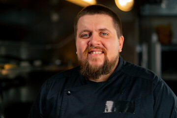 close-up in professional kitchen portrait of a chef in a black jacket in the kitchen happy smile