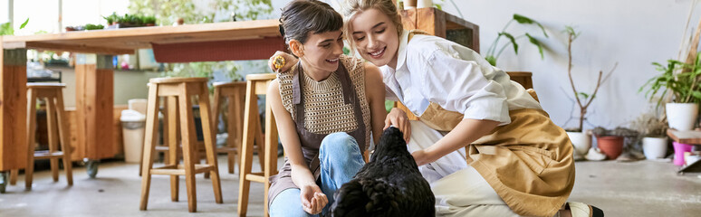 Two women in an art studio showing affection to a black hen.