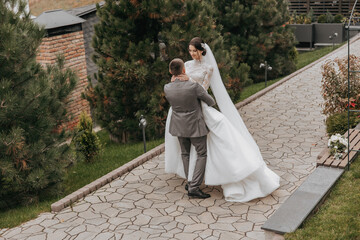 Naklejka premium A bride and groom are dancing on a brick walkway. The bride is wearing a white dress and the groom is wearing a suit