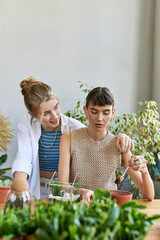 Lesbian couple immersed in creative conversation at art studio table.