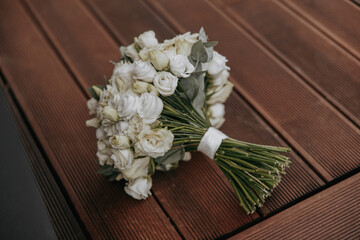 A bouquet of white flowers sits on a wooden table. The flowers are arranged in a way that they are all facing the same direction, creating a sense of unity and harmony