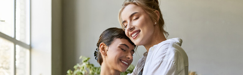 Two women, a loving lesbian couple, stand together in an art studio.