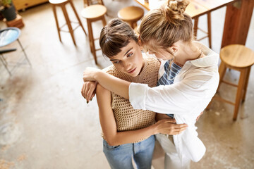Two women in art studio sharing a tender embrace.